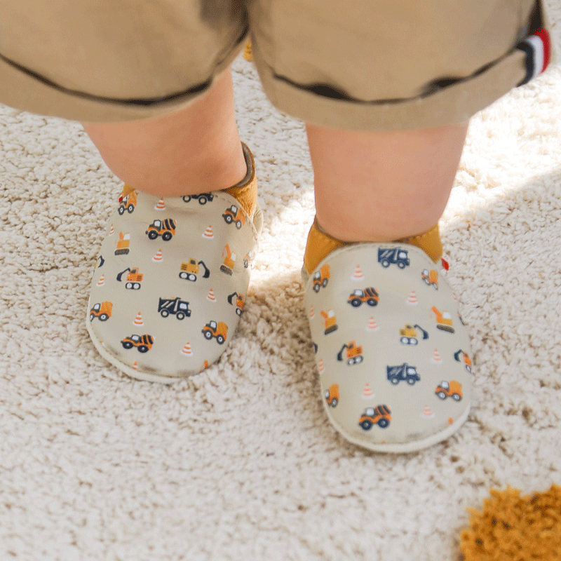 chaussons en cuir souple motifs engins de travaux portés par un bébé