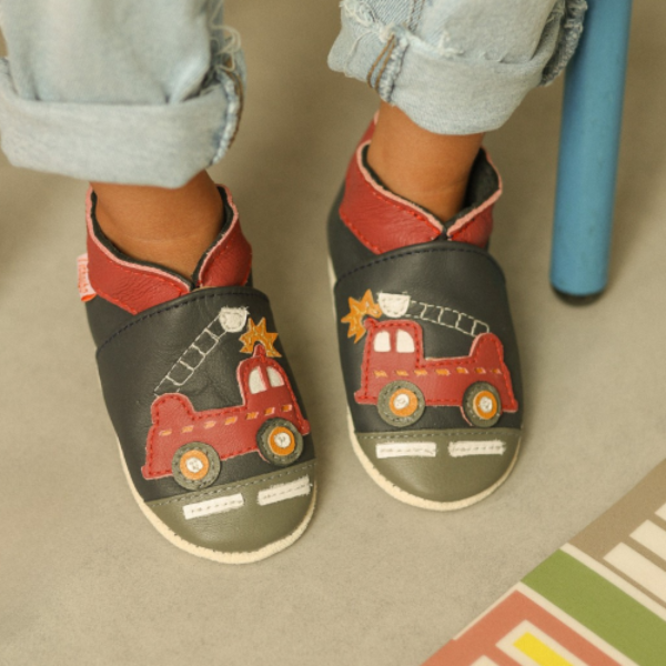 photo de chaussons avec motifs camions de pompiers en cuir cousus, portés par par un enfant
