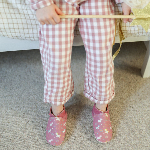 chaussons cuir souple rose imprimé licornes portés par un enfant