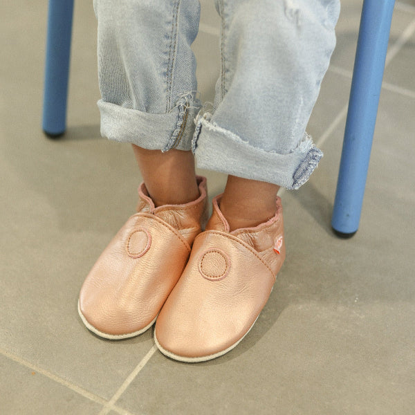 Photo de chaussons en cuir souple rose irisé portés par un enfant