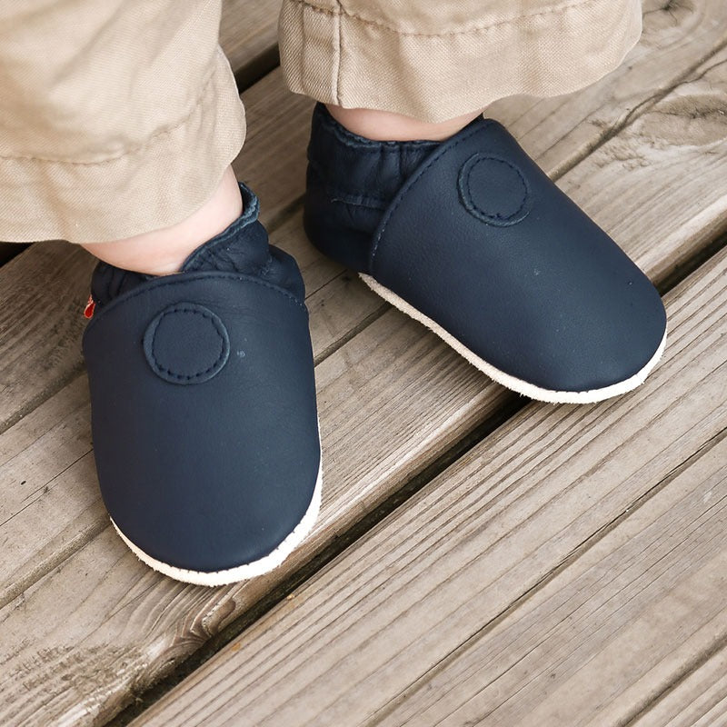 Chaussons en cuir souple couleur bleu marine portés par un enfant