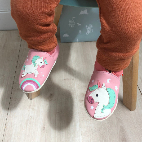 Chaussons rose en cuir souple motifs licorne portés par un bébé