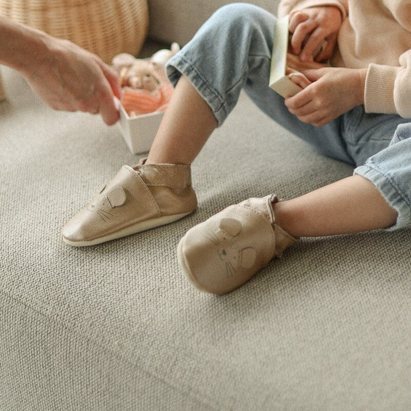 Chaussons petite tête de souris en cuir souple rose irisé porté par un bébé