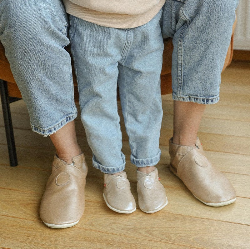 Photo des chaussons en cuir souple beige irisé portés par un adulte et eu enfant