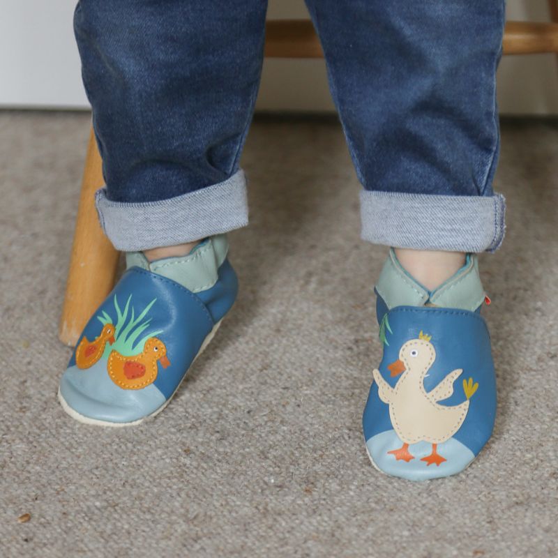 Chaussons en cuir souple bleu avec des canards portés par un bébé