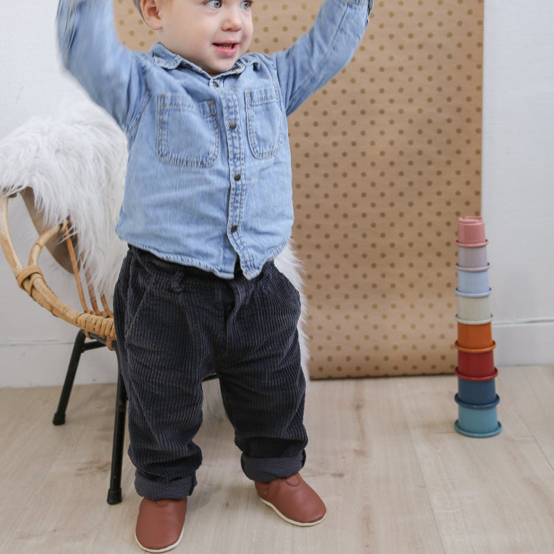 Chaussons cuir souple marron fourrés portés par un bébé