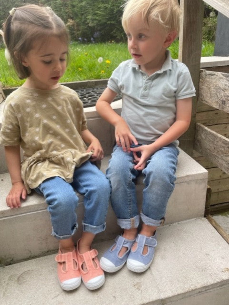 Chaussures toiles Helly Bleu jean et rose pêche portées par des enfants dans un jardin