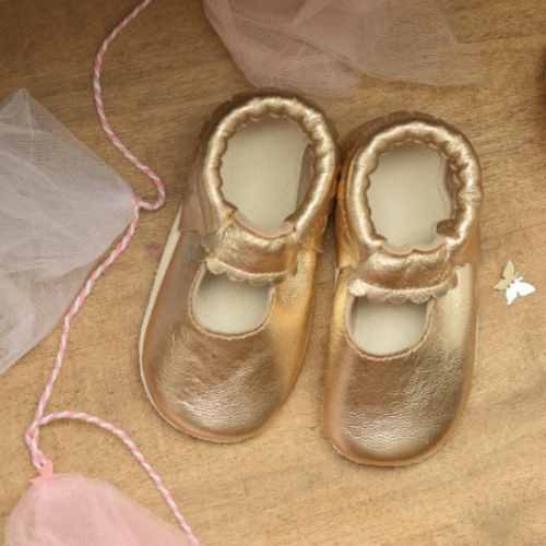 photo d'ambiance chaussons bébé ouvert doré vue de dessus dans une mise en ambiance féérique.