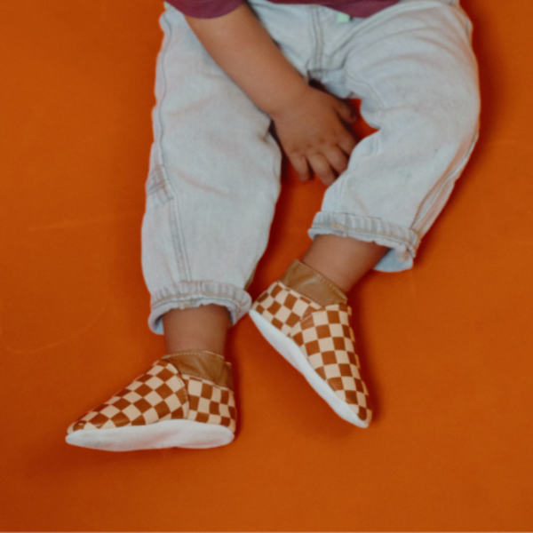 Photo des chaussons enfant en cuir souple Suzon le damier portés par un enfant.
