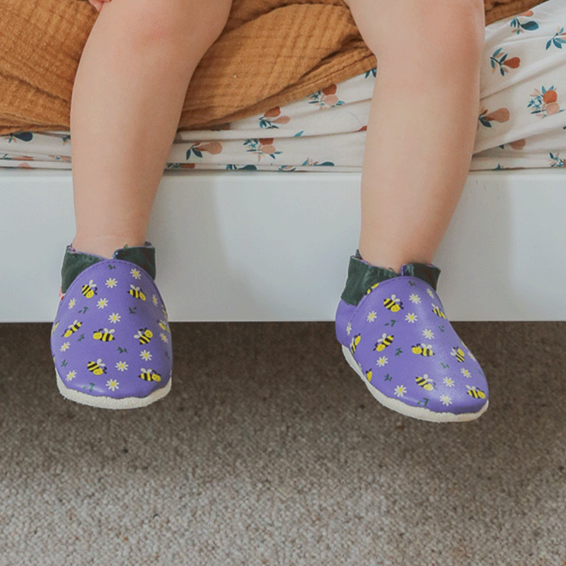 Chaussons cuir souple violet motifs abeilles portés par un bébé