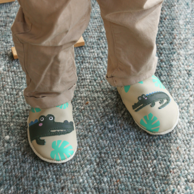Chaussons cuir souple motifs crocodiles cousus portés par un enfant.