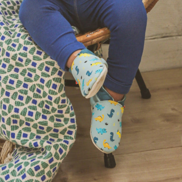 Chaussons en cuir souple bébé Nestor les dinosaures portés pas un bébé.