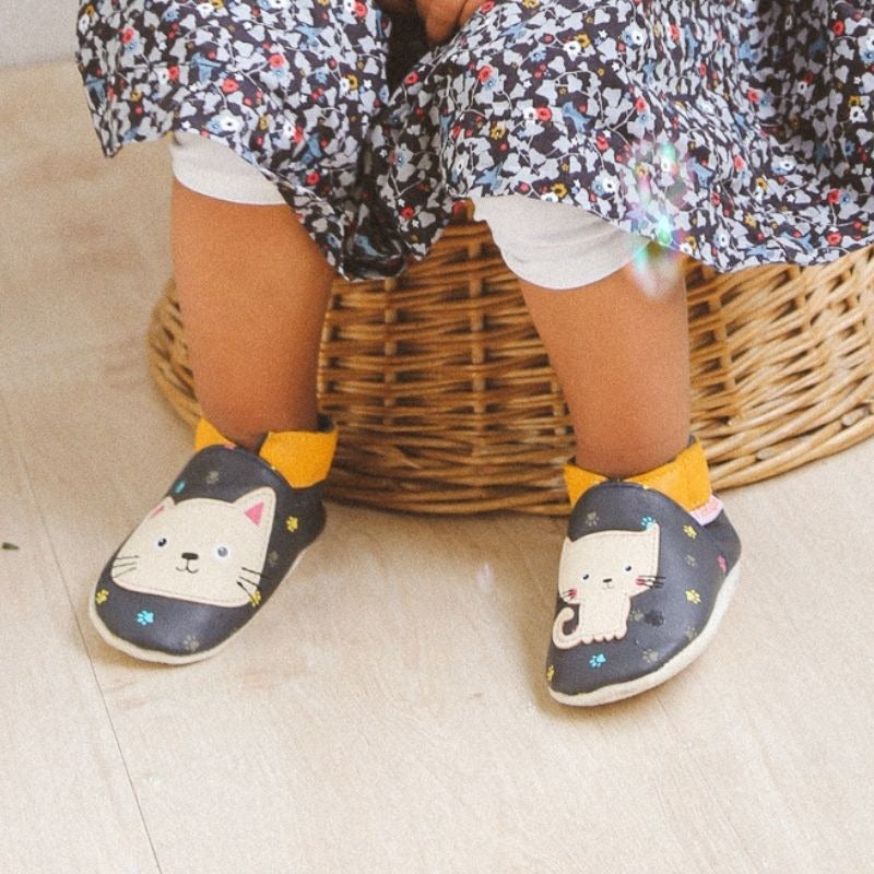 Chaussons bebe cuir souple Nina le chat prisent en portés par un bébé.