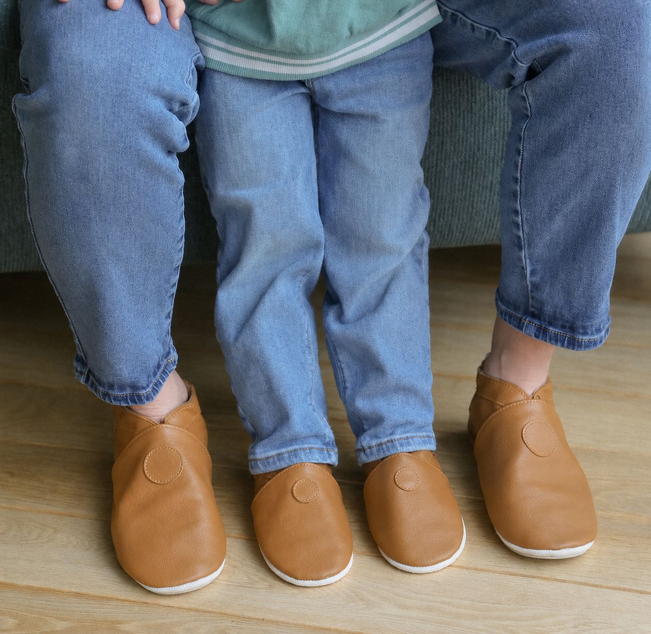Chaussons en cuir souple coloris café portés par un enfant et un adulte