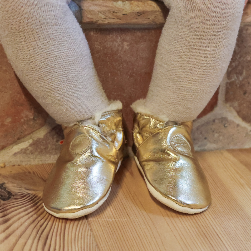 Chaussons cuir souple fourrés uni doré portés par un bébé